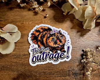 May include: A die-cut sticker featuring a fluffy orange and black tortoiseshell cat wearing a purple tiara and collar. The cat has an open mouth and wide eyes. Below the cat, the text reads This is an outrage! in bold purple letters.