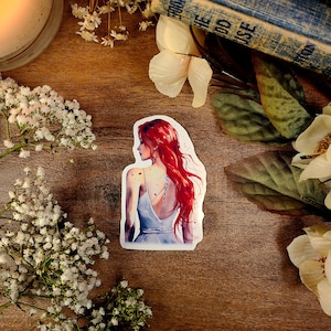 K&ouml;nnte beinhalten: Eine Aquarell-Illustration einer Frau mit langen, flie&szlig;enden roten Haaren. Sie tr&auml;gt ein wei&szlig;es Kleid und hat ein Tattoo auf dem R&uuml;cken. Die Illustration ist auf wei&szlig;em Hintergrund.