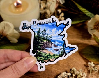 May include: A sticker of the outline of New Brunswick, Canada, with a painted scene of a rocky coastline and trees. The sticker is white with black outlines and a blue, green, and white painted scene.
