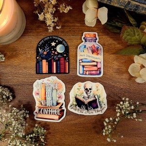 May include: Four colorful stickers with book-themed illustrations and text. The first sticker features a stack of books with the text "I have lived a thousand lives". The second sticker features a glass bottle filled with books with the text "Anti Depressants". The third sticker features a stack of books with the text "I have no shelf control". The fourth sticker features a skeleton reading a book with the text "Just one more chapter".