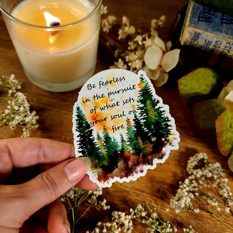 Puede incluir: Una pegatina de acuarela con una escena de bosque y la cita "S&eacute; valiente en la b&uacute;squeda de lo que enciende tu alma".