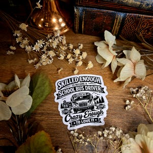 Puede incluir: Una pegatina blanca con texto negro que dice "Skilled Enough to Become a School Bus Driver" y "Crazy Enough to Love It". La pegatina presenta una ilustración de autobús escolar, señales de stop y un paisaje montañoso.