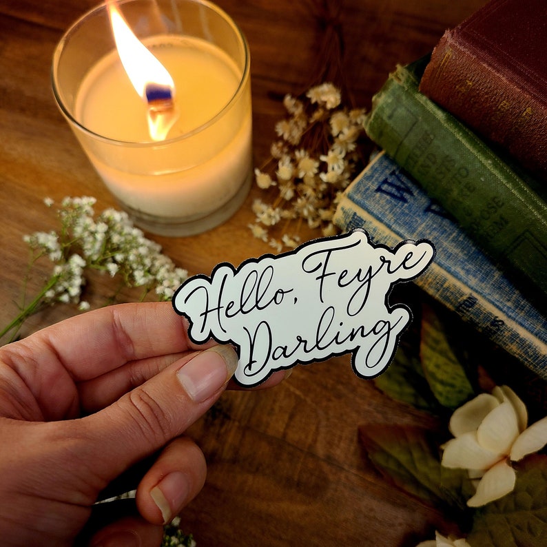 K&ouml;nnte beinhalten: Wei&szlig;er Aufkleber mit schwarzer Aufschrift "Hello, Feyre Darling".