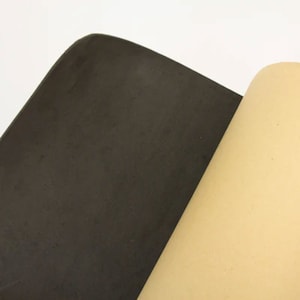 May include: A close-up of a black foam sheet with a beige sheet folded over the top edge.