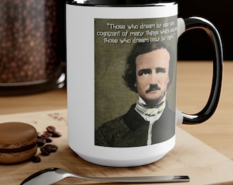 Puede incluir: Taza de cerámica blanca con asa y borde negros, con un retrato de Edgar Allan Poe y una cita. La cita dice: "Los que sueñan de día son conscientes de muchas cosas que escapan a los que solo sueñan de noche."