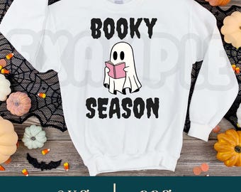 May include: White sweatshirt with a ghost reading a book and the text "Booky Season".