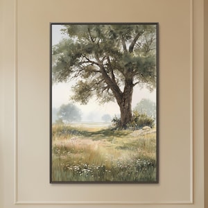 May include: A framed landscape painting depicts a large tree in a field with a path leading into the distance. The artwork features soft colors of green, brown, and beige, creating a serene and natural scene. The painting is displayed in a living room setting.