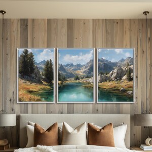 May include: A bedroom featuring a bed with a neutral-toned comforter and pillows. Above the bed, three framed landscape paintings depict a serene lake scene surrounded by mountains and trees. The wall is made of light-colored wood panels.