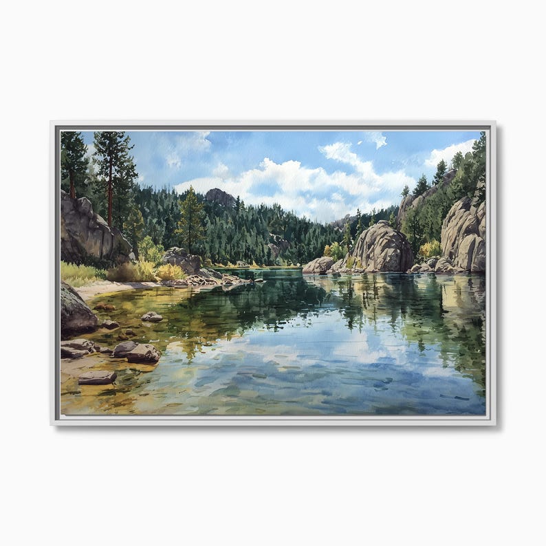 May include: A framed landscape painting depicts a serene lake scene. The water reflects the sky and surrounding trees. Large rocks and a shoreline are visible. The painting is set in a white frame.