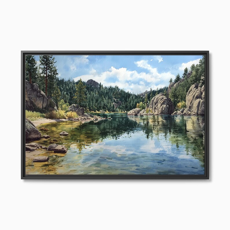 May include: A framed landscape painting depicts a serene lake scene. The artwork features a calm, reflective lake surrounded by lush green trees, large rock formations, and a bright blue sky with fluffy white clouds. The painting is encased in a black frame.