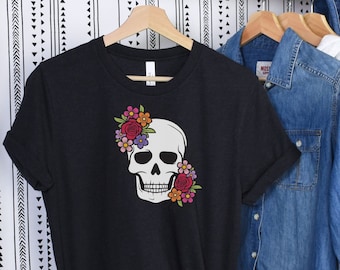May include: Black t-shirt with a white skull graphic and colorful floral design. The skull is wearing a flower crown.