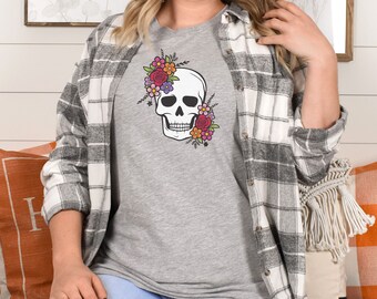 May include: A gray t-shirt with a white skull design surrounded by colorful flowers. The skull has a floral crown and the flowers are pink, purple, red, and orange.