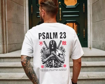 May include: White t-shirt with a graphic design on the back. The design features a warrior with swords, floral elements, and the text "PSALM 23" in black. Below the graphic is the text "EVEN THOUGH I WALK THROUGH THE VALLEY OF THE SHADOW OF DEATH, I WILL FEAR NO EVIL."