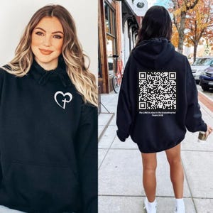 May include: Black hoodie with a white heart and cross design on the front and a QR code with the text "The LORD is close to the brokenhearted Psalm 34:18" on the back.
