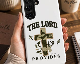 May include: A white smartphone case featuring a camouflage-patterned cross in the center. The text THE LORD is printed above the cross, and PROVIDES PHIL 4:19 is printed below. The design includes small illustrations of a deer, fish, and birds.