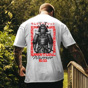 May include: White t-shirt with a black and white illustration of a samurai warrior. The text "Spiritual Warrior 6:11" is printed in red on the shirt. The text "サムラ"." is printed in Japanese on the shirt.