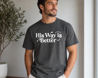 May include: A charcoal gray short-sleeve t-shirt featuring the white text His Way is Better with small star icons and the reference Isaiah 55:8-9 printed on the front. The shirt has a crew neckline and a standard fit, made of cotton fabric.