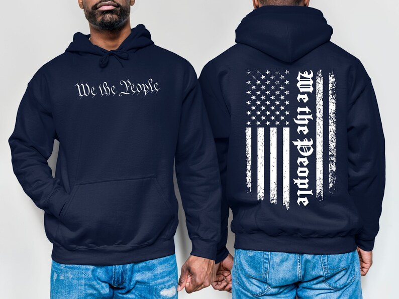 K&ouml;nnte beinhalten: Zwei marineblaue Kapuzenpullover mit einem wei&szlig;en, abgenutzten amerikanischen Flaggenmuster auf der R&uuml;ckseite. Ein Pullover hat den Text "We the People" in Wei&szlig; auf der Vorderseite.