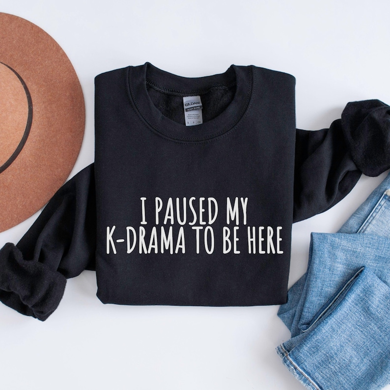 May include: Black sweatshirt with the text "I paused my K-drama to be here" in white.