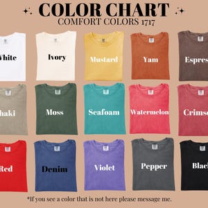 May include: Color chart of Comfort Colors 1717 t-shirts. The chart displays various colors, including white, ivory, mustard, yam, espresso, khaki, moss, seafoam, watermelon, crimson, red, denim, violet, pepper, and black. Each shirt is folded and labeled.