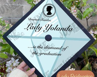 May include: A graduation cap with a black border and a light blue center. The cap features the text "Dearest Reader, Lady Yolanda...is the diamond of the graduation." A silhouette of a graduate is in a circle.
