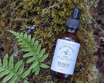 May include: A brown glass bottle with a dropper top and a white label that reads "Of the Valley Herbs Est. 2020 Reishi Herbal Tincture 2 ounces". The bottle is sitting on a bed of green moss.