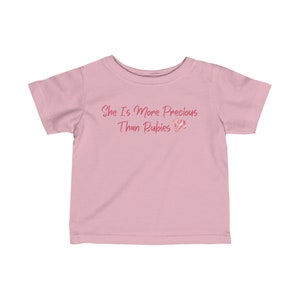 May include: Pink short-sleeved t-shirt with the text "She is more precious than rubies" and a pink diamond graphic.