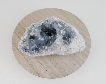 May include: A large, light blue and white celestite crystal cluster with a natural, rough exterior. The crystal has a large, open cavity in the center, revealing the intricate, sparkling formations inside.