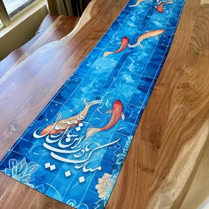 May include: A rectangular blue table runner featuring a koi fish design. The runner has a blue tile pattern with koi fish in shades of red, orange, and white. Decorative floral elements and calligraphy are also present.