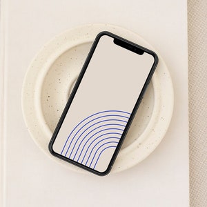 Puede incluir: Un teléfono inteligente negro con un fondo blanco y un diseño abstracto azul y blanco en la pantalla.