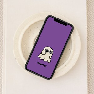 May include: A purple phone background with a cartoon ghost wearing heart-shaped sunglasses and the text "Spooky!"