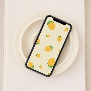 May include: A black smartphone with a white background and a pattern of yellow lemons with green leaves.