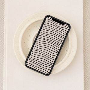 Puede incluir: Un teléfono inteligente negro con un fondo blanco y un patrón de líneas onduladas en la pantalla.