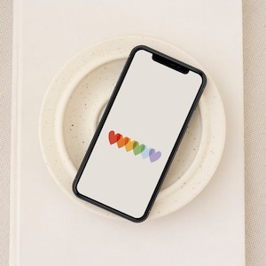 May include: A smartphone with a white background and a row of rainbow-coloured hearts on the screen.