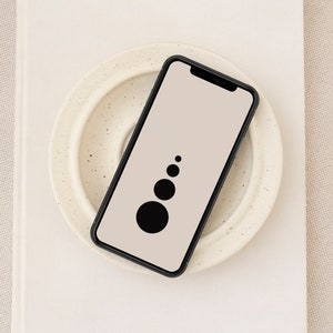 Puede incluir: Un teléfono inteligente negro con un fondo blanco y un diseño simple de círculo negro en la pantalla.