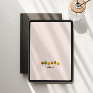 Può includere: Un tablet digitale con uno sfondo rosa e una fila di alberi stilizzati in colori autunnali. Il testo "autunno" è scritto sotto gli alberi.