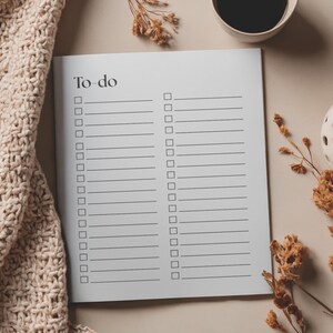 May include: A white To-Do list notepad with a minimalist design. The notepad features a header with the words "To-do" and a series of checkboxes. A beige knitted blanket, a cup of coffee, and decorative dried flowers are also in the image.
