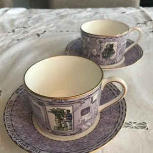 May include: Two teacups and saucers from The Millennium Collection. The cups and saucers are lavender with gold trim. The cups feature illustrations of a man operating a camera and other images. The saucers have a repeating pattern.