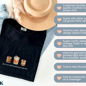 Może przedstawiać: Czarny t-shirt unisex z napisem "just an old fashioned girlie" i grafiką koktajli. Koszulka jest połączona z niebieskimi dżinsami i beżowym kapeluszem. Wykonana w 100% z bawełny.