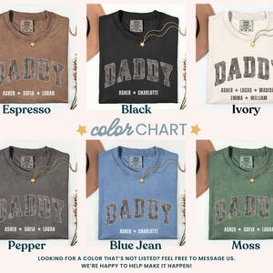 K&ouml;nnte beinhalten: Eine Farbkarte zeigt sechs T-Shirts in verschiedenen Farben: Espresso, Schwarz, Elfenbein, Pfeffer, Blue Jean und Moos. Jedes Shirt tr&auml;gt das Wort "DADDY" in einer verwaschenen Schrift im College-Stil, mit Namen darunter. Eine goldene Halskette ist auf jedem Shirt drapiert.