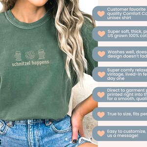 May include: Green unisex t-shirt with the phrase "schnitzel happens" and pretzel and beer stein graphics. The shirt is made of 100% cotton and has a relaxed fit. The shirt is a Comfort Colors 1717 unisex shirt.