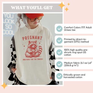 May include: White unisex t-shirt with a red raccoon graphic and the text "PREGNANT AND HERE FOR THE SNACKS".