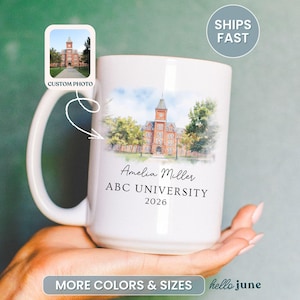 May include: White ceramic mug featuring a watercolor illustration of a university building. The mug includes the name "Amelia Miller", "ABC UNIVERSITY", and the year "2026". A small image of the building is in the upper left corner. The mug is held by a person.