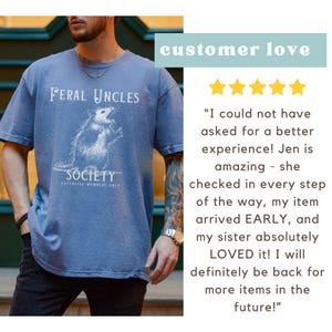 May include: A blue t-shirt with a white graphic of an opossum and the text "Feral Uncles Society Exclusive Members Only".