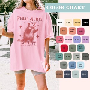 May include: Pink oversized t-shirt with a graphic of a possum and the text "Feral Aunts Society Exclusive Members Only".