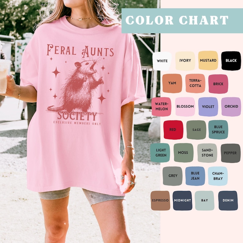 May include: Pink oversized t-shirt with a graphic of a possum and the text "Feral Aunts Society Exclusive Members Only".