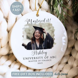 May include: White ceramic graduation ornament with a photo of a graduate in a cap and gown. The ornament has the text "Mastered it!" and the graduate's name, university, degree, and year.