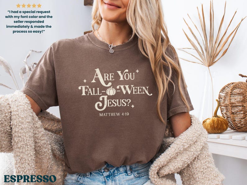 May include: Espresso-colored t-shirt with the text "Are You Fall-Ween Jesus?" in a cream-colored font. The shirt also features the text "Matthew 4:19". The shirt is part of a fall-themed collection.