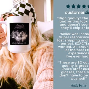 May include: White ceramic mug featuring a black and white ultrasound image. The mug has the text "Baby Johnson" in a script font. The mug is held up by a person.