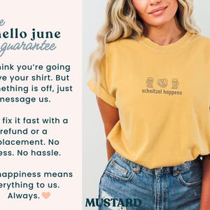 May include: Mustard-colored t-shirt with the phrase "schnitzel happens" and small graphic icons. The shirt has rolled-up sleeves and is paired with blue denim shorts. The text "hello june guarantee" is also visible.